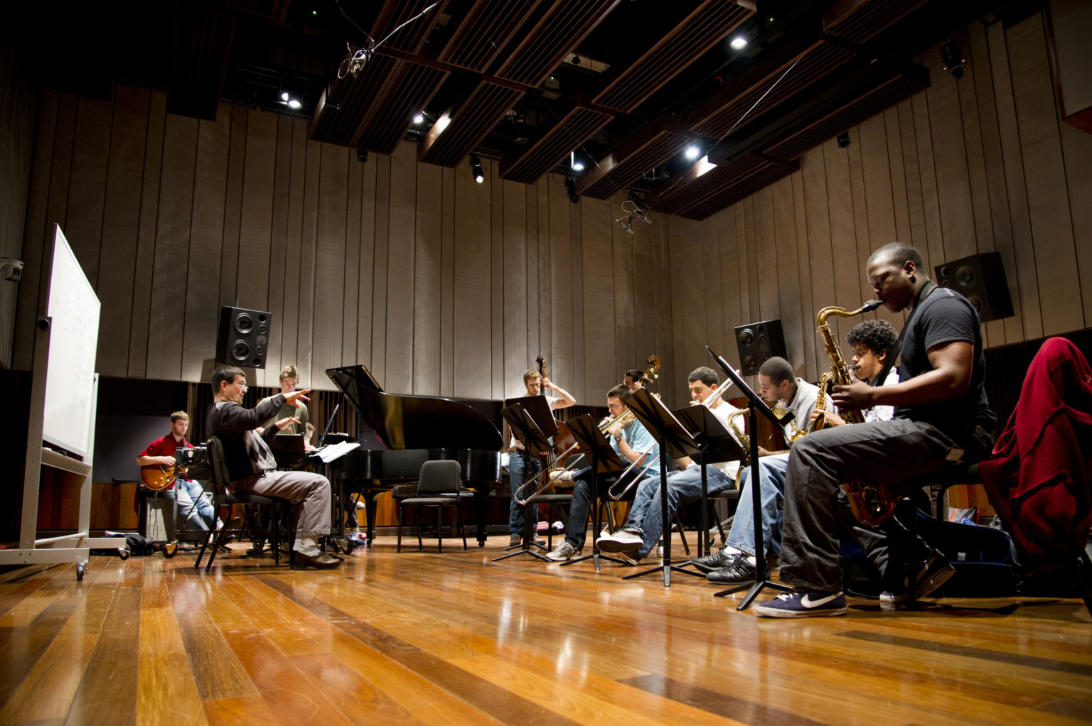 Wood floors and grey acoustic wall and ceiling paneling with musicians rehearsing at Kohl Building Wood floors and grey acoustic wall and ceiling paneling with musicians rehearsing at Kohl Building
