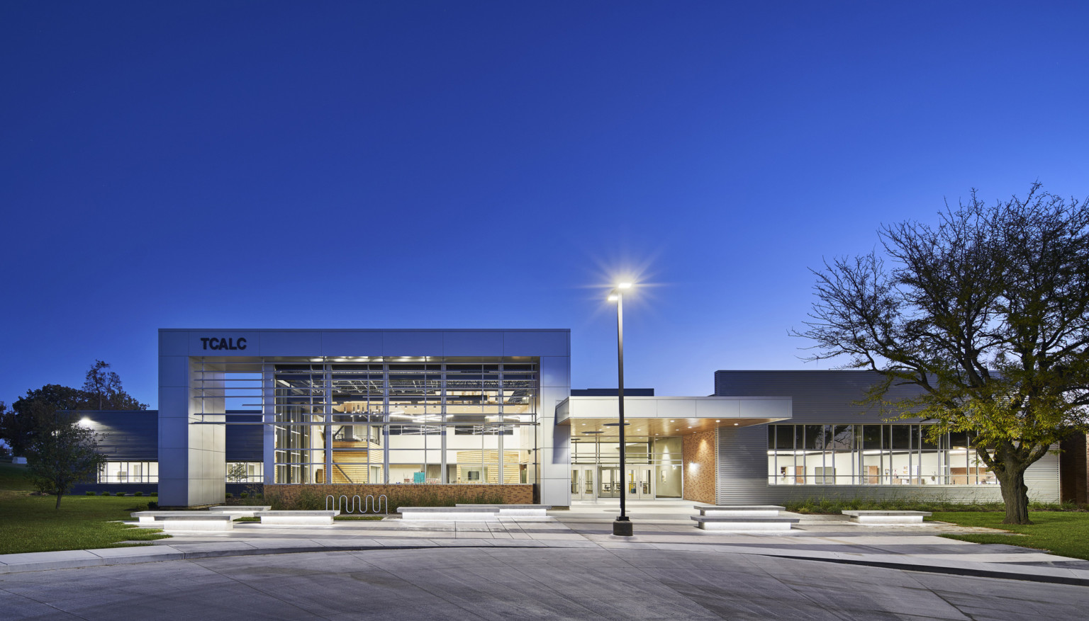 evening exterior view of school with floor to ceiling windows and lighting at Topeka Center for Advanced Learning & Careers