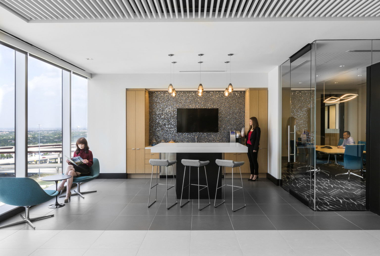 Seating area at Granite Park III. Glass walled office, right, and floor to ceiling windows, left, frame screen, green chairs