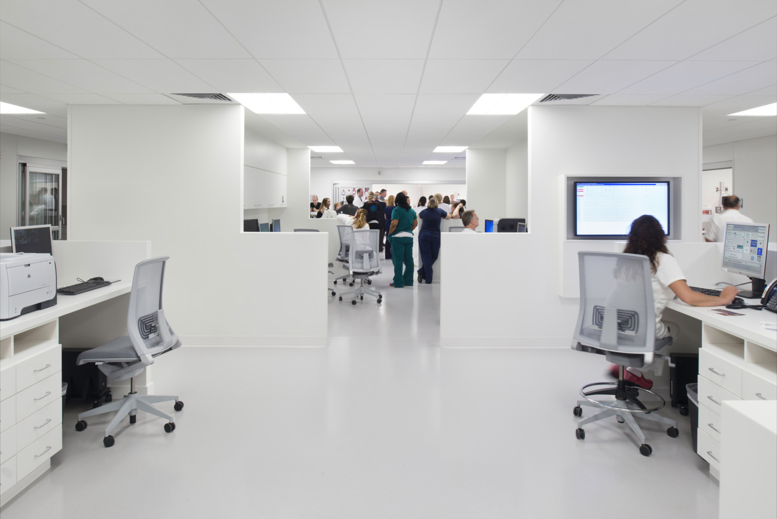 medical professional collaborating and working in a symmetrical white office with desks along both sides