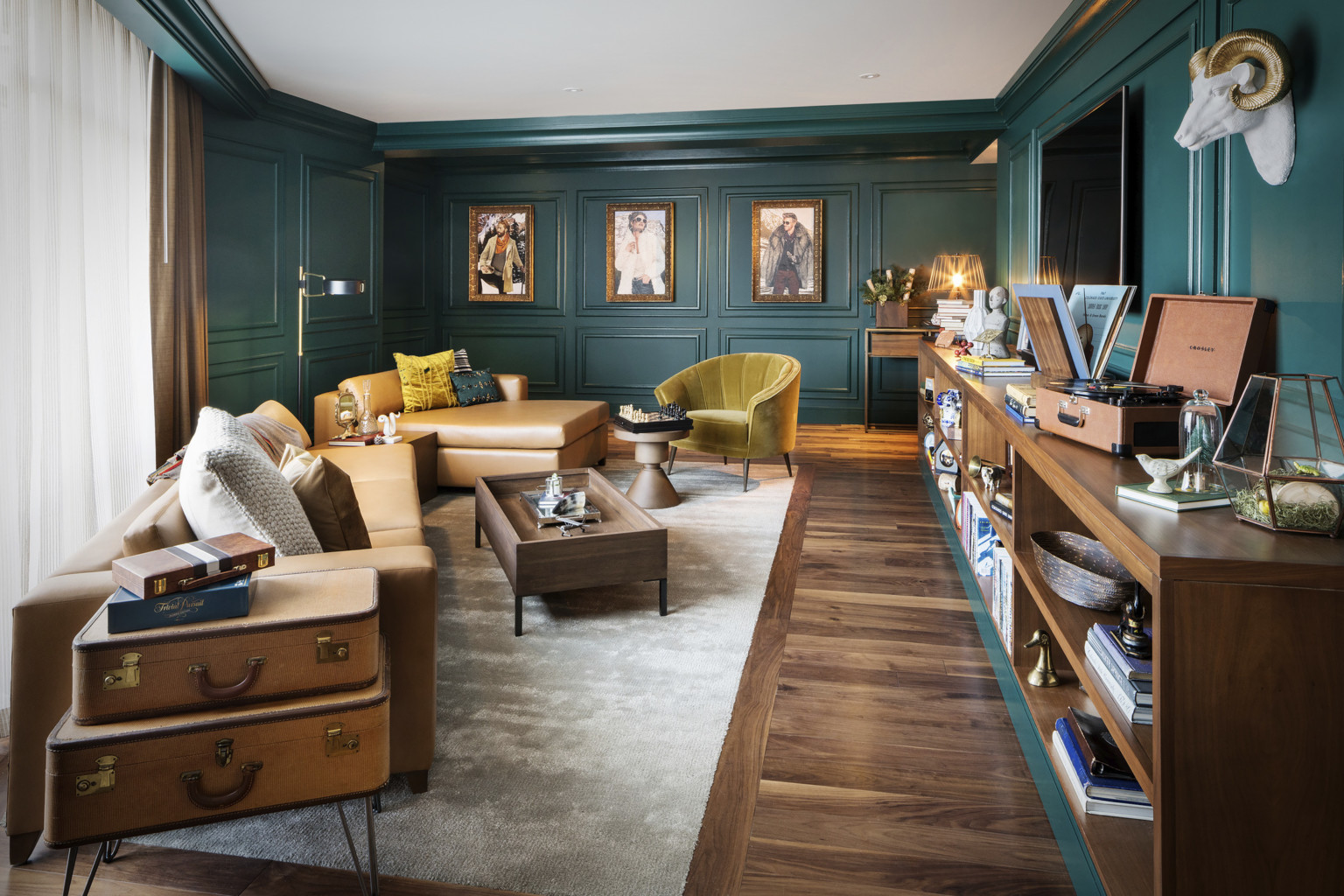 Sitting room with dark green molded walls. Light brown leather couch and yellow velvet chair with wood coffee table and shelf Sitting room with dark green molded walls. Light brown leather couch and yellow velvet chair with wood coffee table and shelf