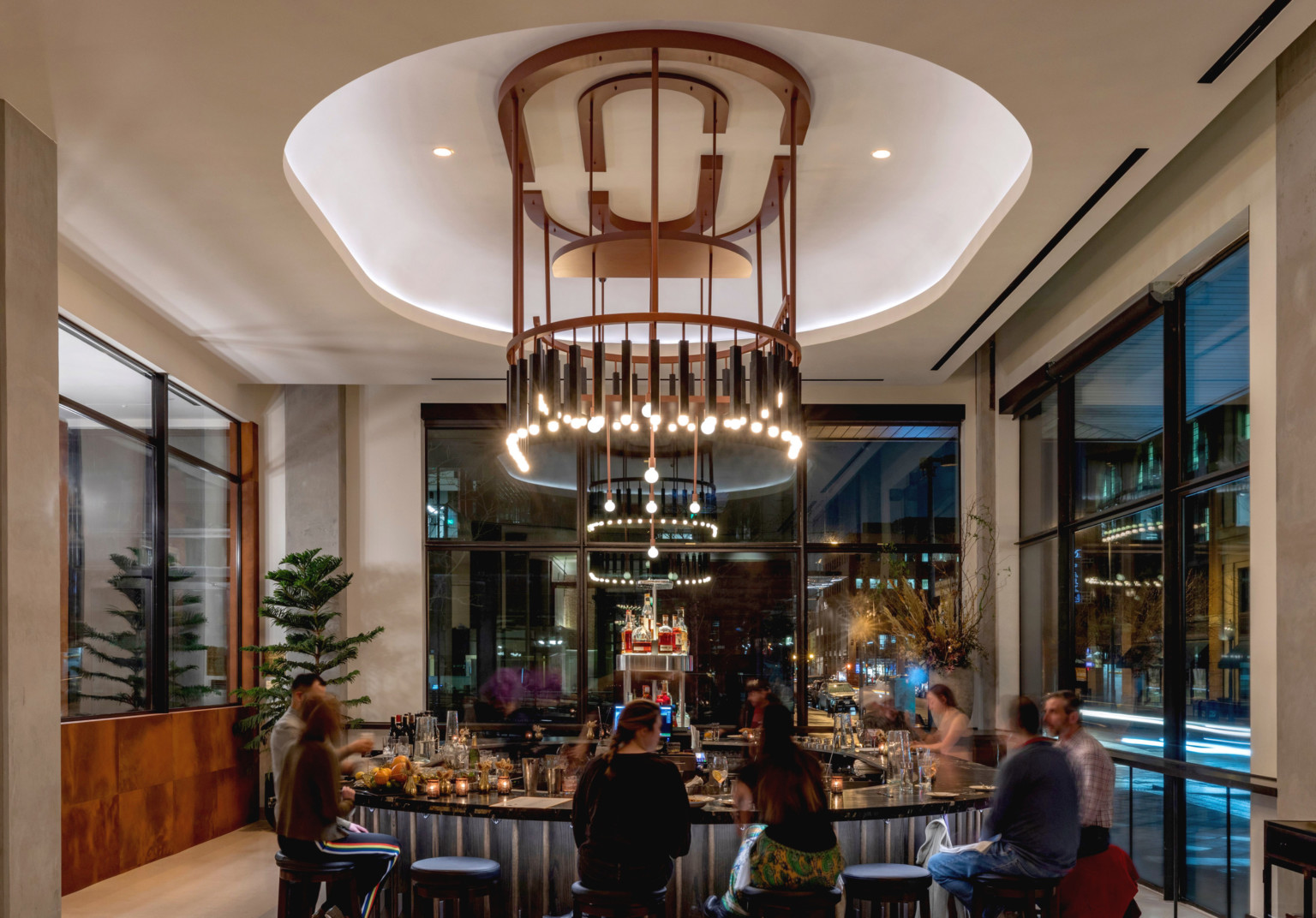 Interior of the same lounge space. Round bar at center, shape mirrored with recessed ceiling and elaborate modern chandelier