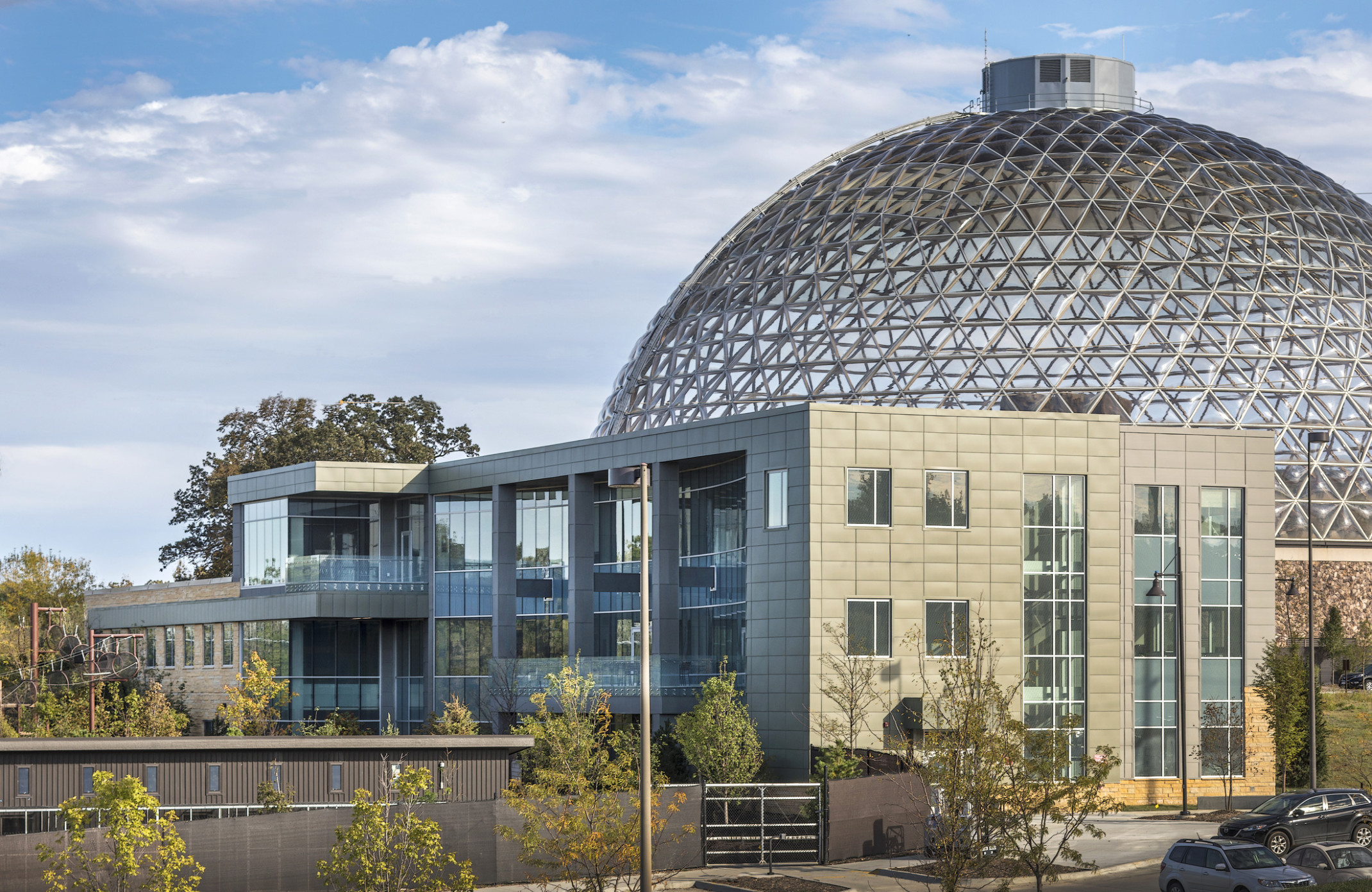 The Omaha Henry Doorly Zoo Education Building with large windows and wrapped facade in front of glass domed building