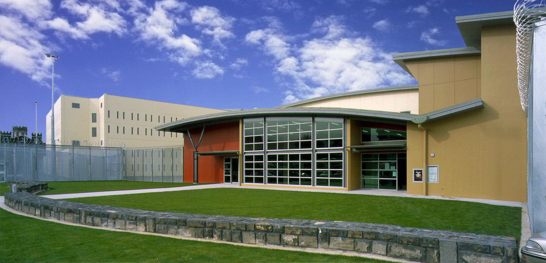 The front entryway of Auckland Central Remand Centre with curved roof and double height windows overlooking a grass lawn