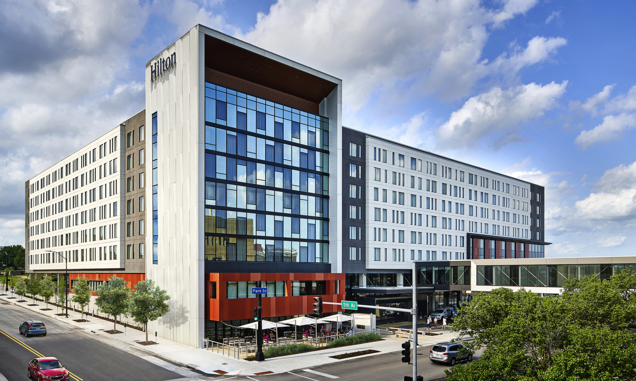 Hilton Des Moines Downtown hotel seen from the front corner. Window front wall shaded by extended white wall with Hilton sign