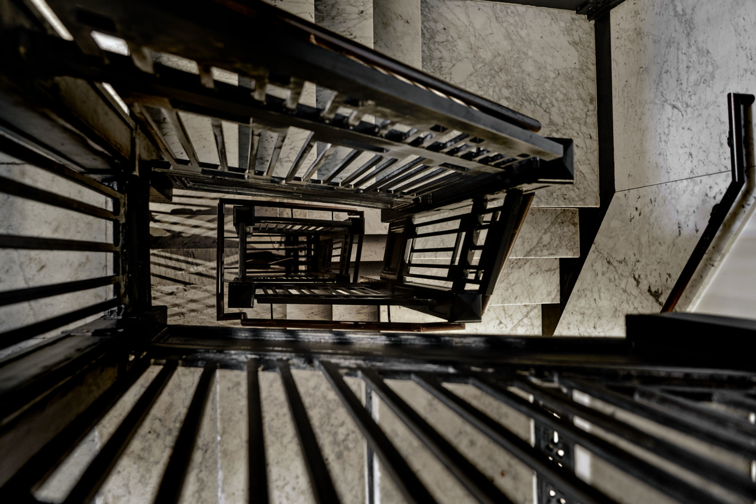 the view down a black wrought iron and marble staircase
