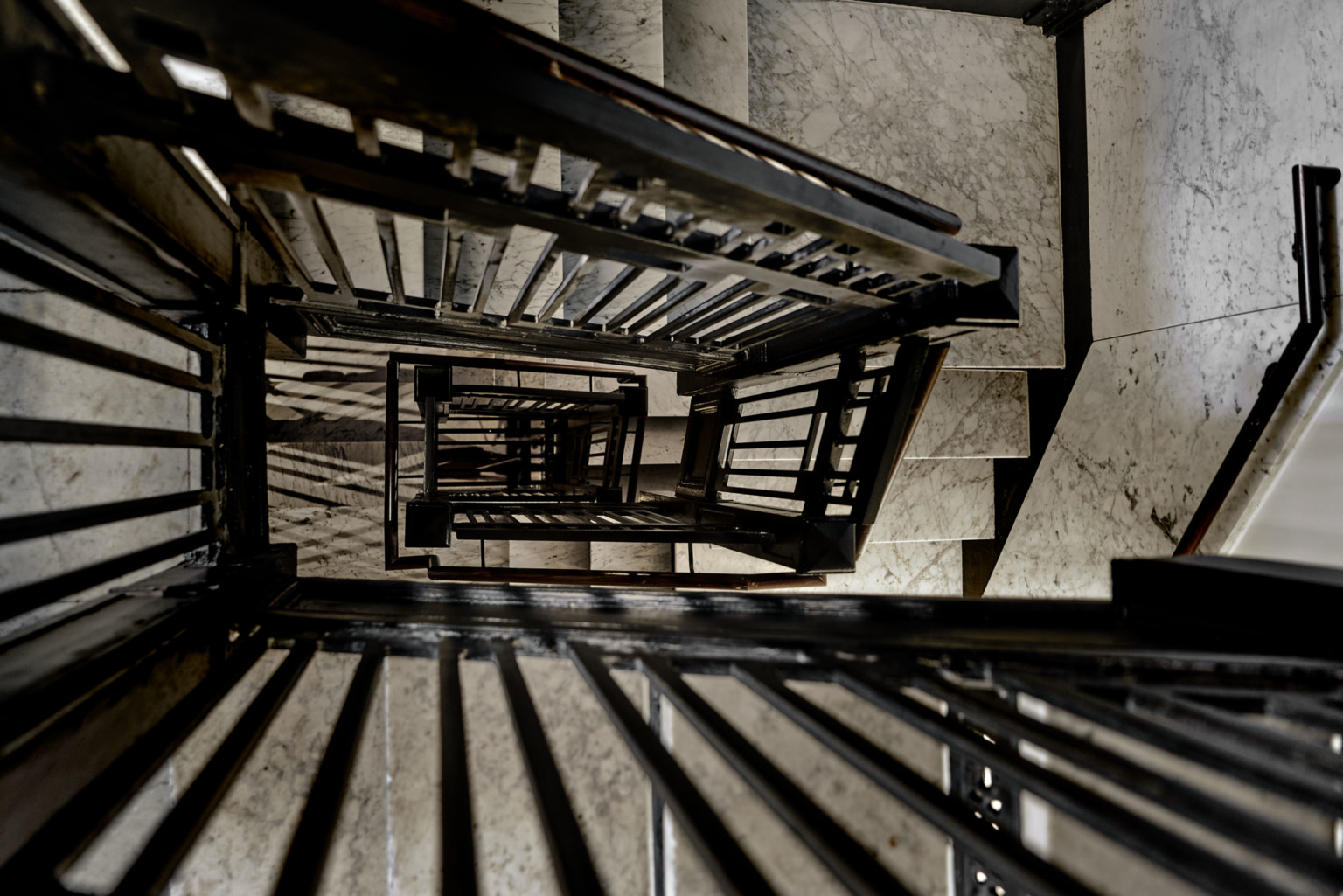 the view down a black wrought iron and marble staircase the view down a black wrought iron and marble staircase