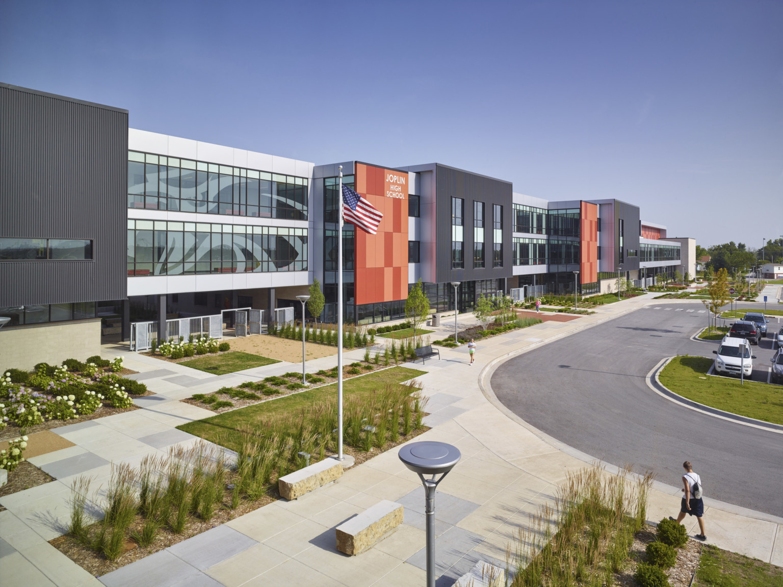 Joplin High School, a 3 story black panel building with recessed white window lined facade and orange accent panels