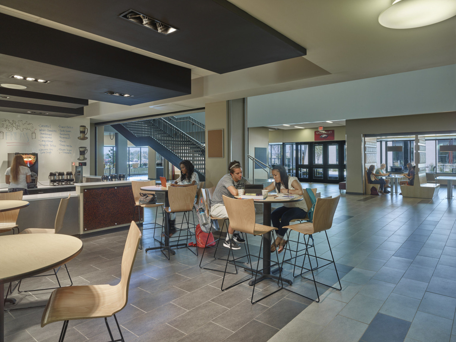 Coffee counter below drop ceiling accents, left. Seating areas on either side of hallway with communicating stairs at center