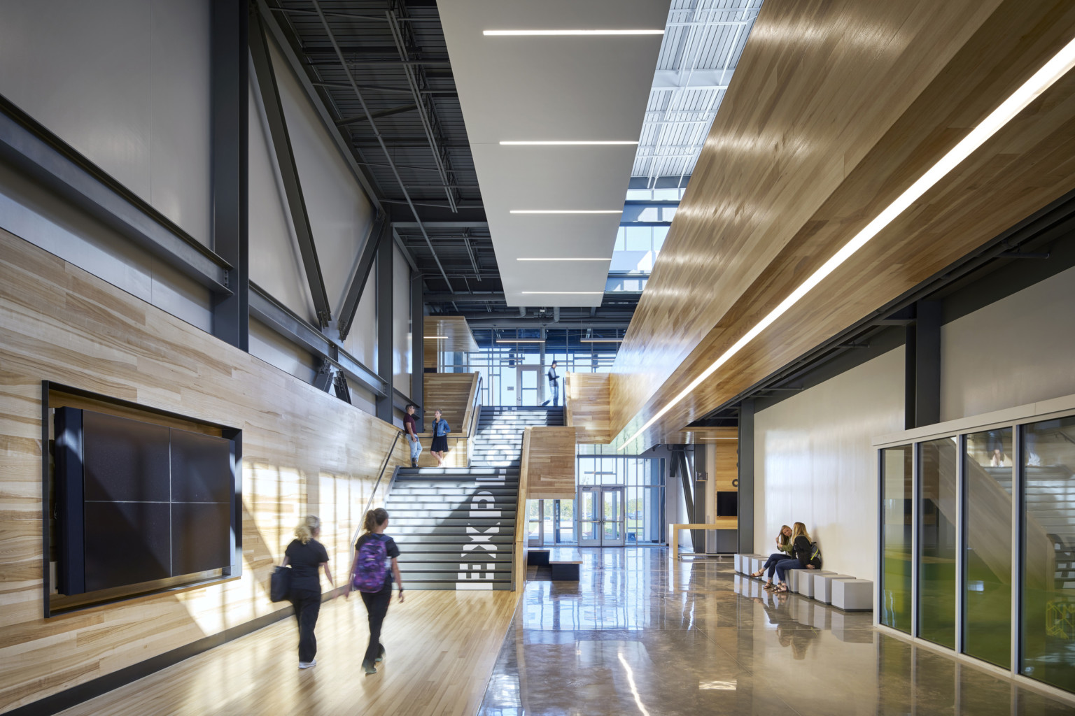 Missouri Innovation Campus interior hallway facing double height glass windows at entry and black staircase with wood walls