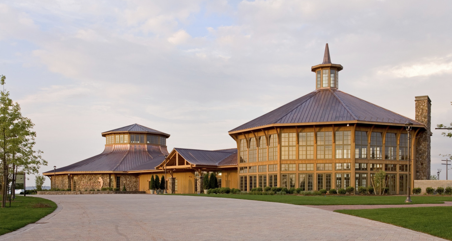 Rounded wood and window building with central spired cupola is connected by a single story entry to a round stone building