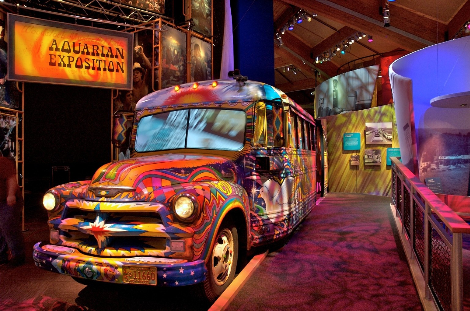 Bus with multicolored abstract painting inside a room with textural colored lighting below a sign reading Aquarian Exposition