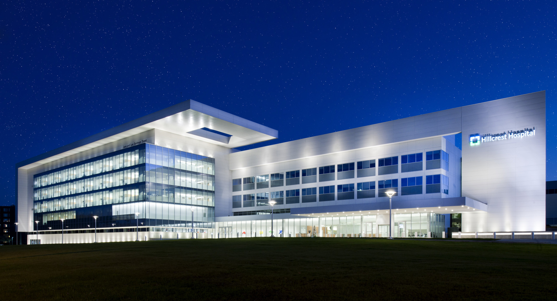 Cleveland Clinic's Hillcrest Hospital at night illuminated from within left, right from recessed light in overhang and below