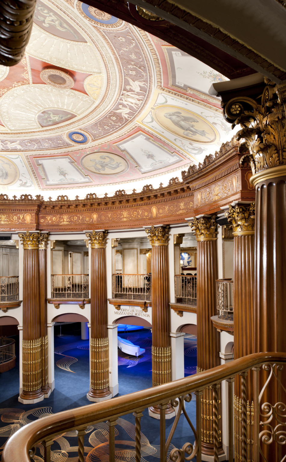 Double height Corinthian columns ascend to ceiling fresco with recessed lights behind crown molding in Allen Theatre rotunda