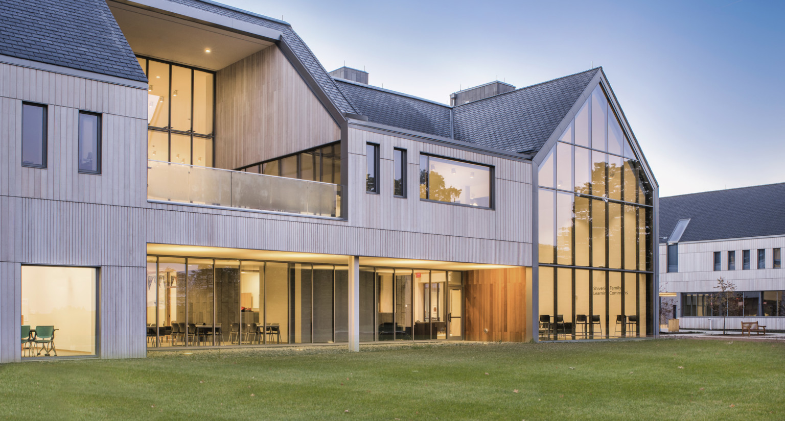 Hawken School's Stirn Hall exterior. A wood panel building with angled dark shingle roof. Pointed triple height windows right