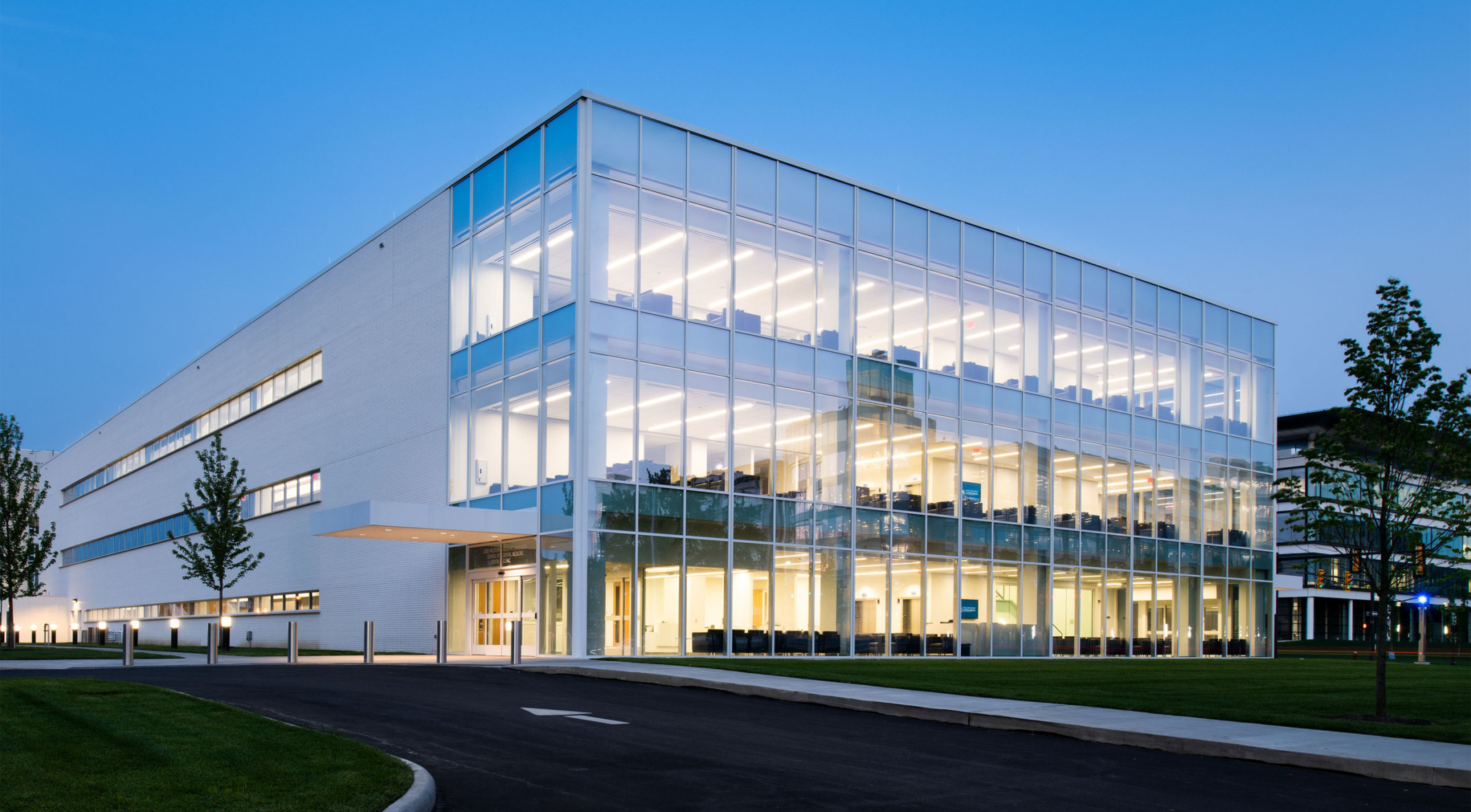 The Case Western Reserve Dental Clinic viewed from the corner illuminated from within at evening, with window walls at front