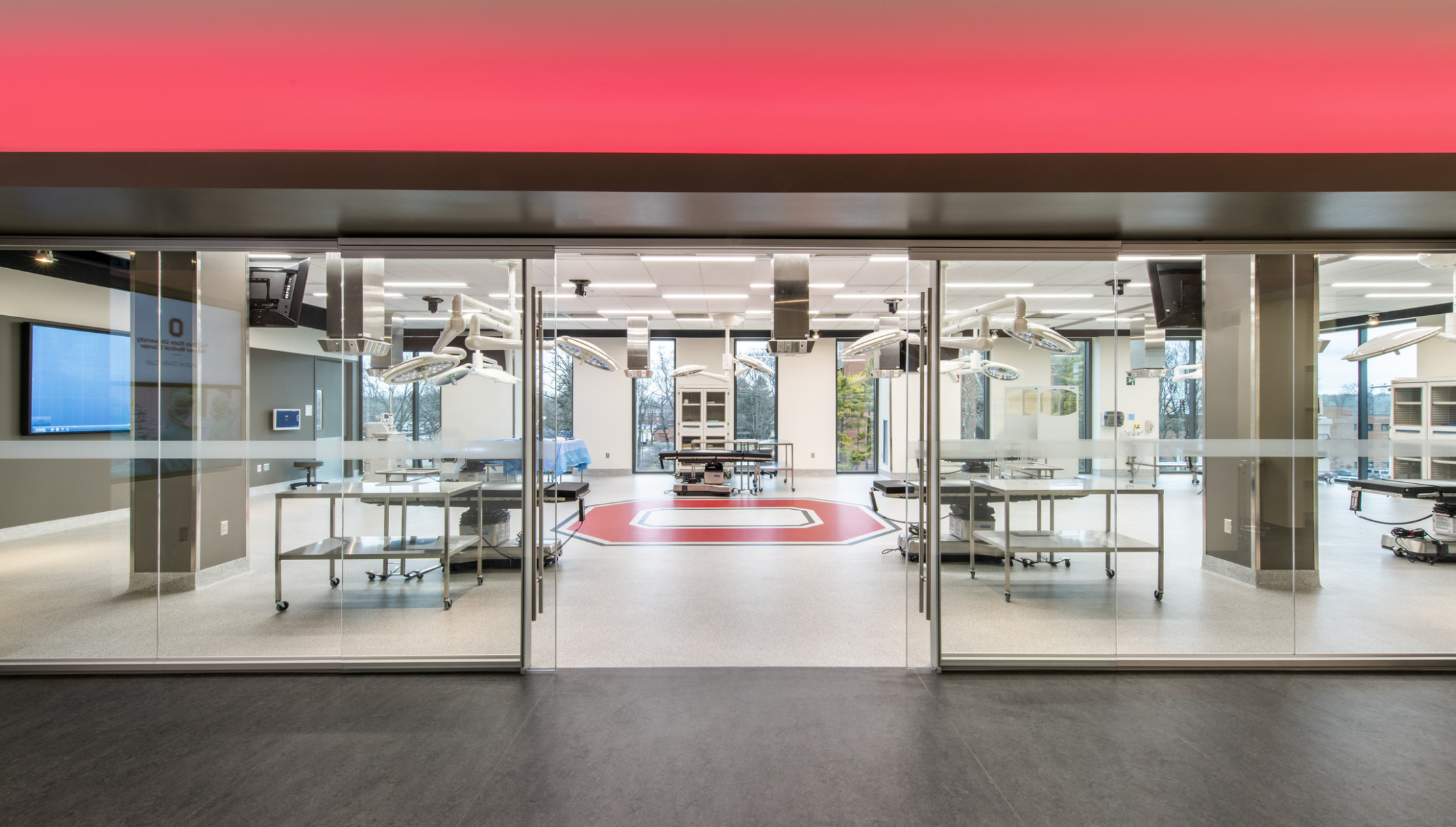 Room in the Jameson Crane Surgical Skills Lab with beds with circular lights suspended above, a large red O on floor center