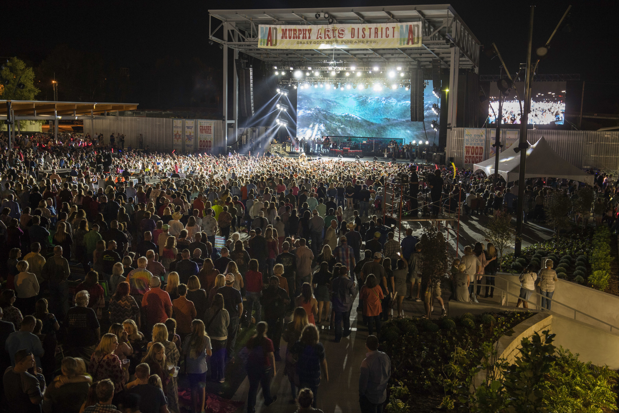 View from above back of crowd at Murphy Arts District concert with band illuminated on stage