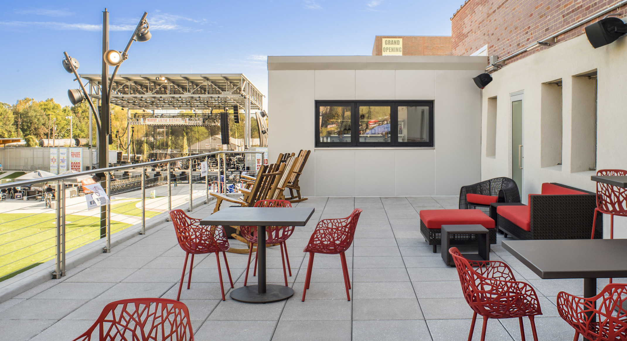 A patio with couches, stools, tables, and rocking chairs overlooks the amphitheater and lawn