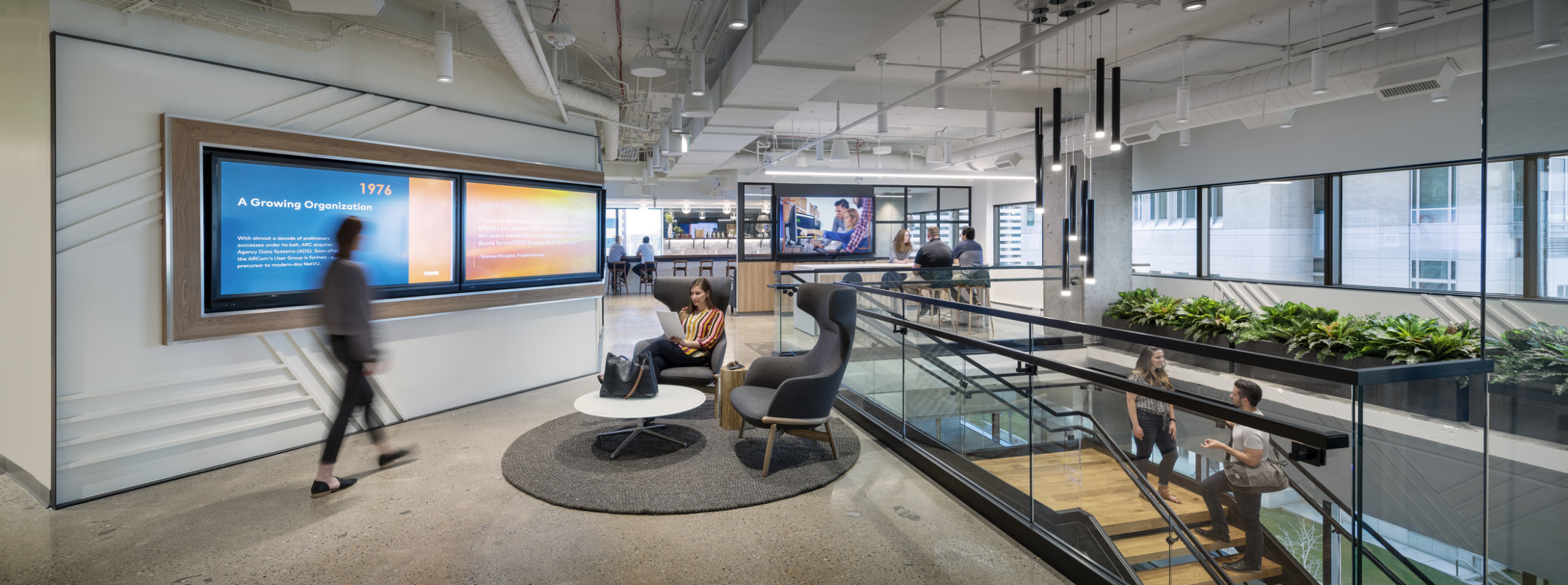 Vista Portfolio Company building interior. Seating areas in front of multiple screens across upper level at the top of stairs