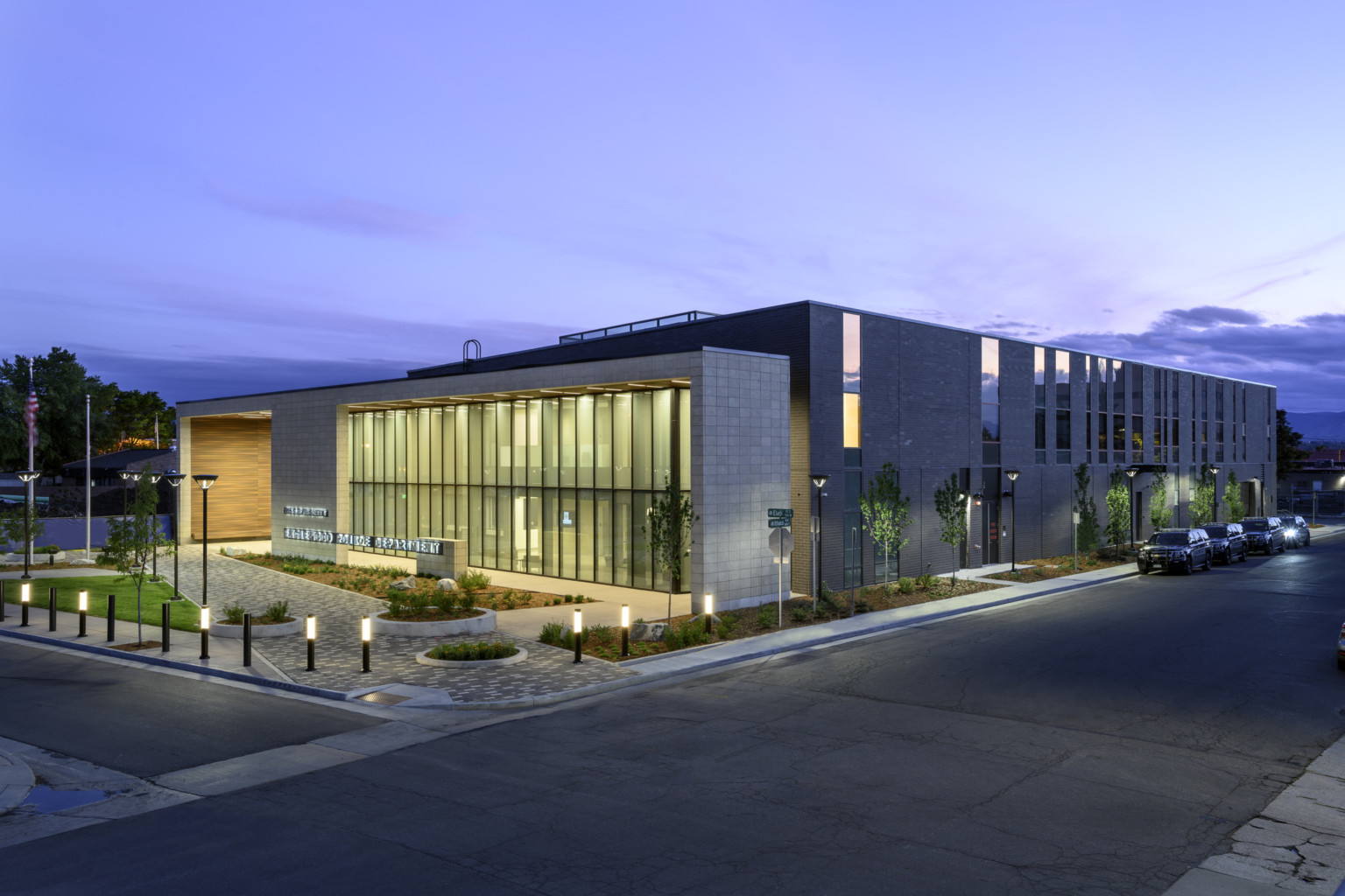 Corner view of building showing full length of structure with entry illuminated in the evening