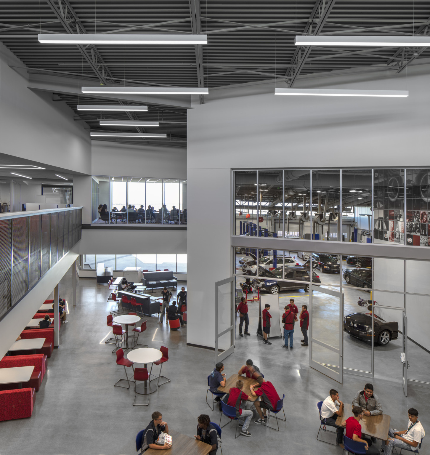View from 2nd floor balcony overlooking seating and glass entrance to double height auto industry and mechanic specific lab, cherry creek innovation campus, ccic cherry creek, cherry creek high school