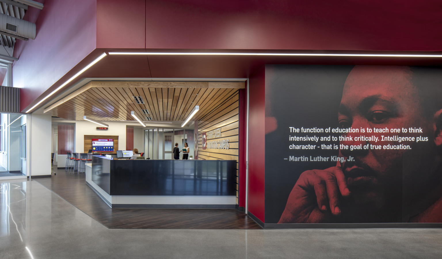 Black reception desk in wood panel recessed room off hallway with photo mural of Martin Luther King Jr. with quote overlaid, cherry creek innovation campus, ccic cherry creek, cherry creek high school