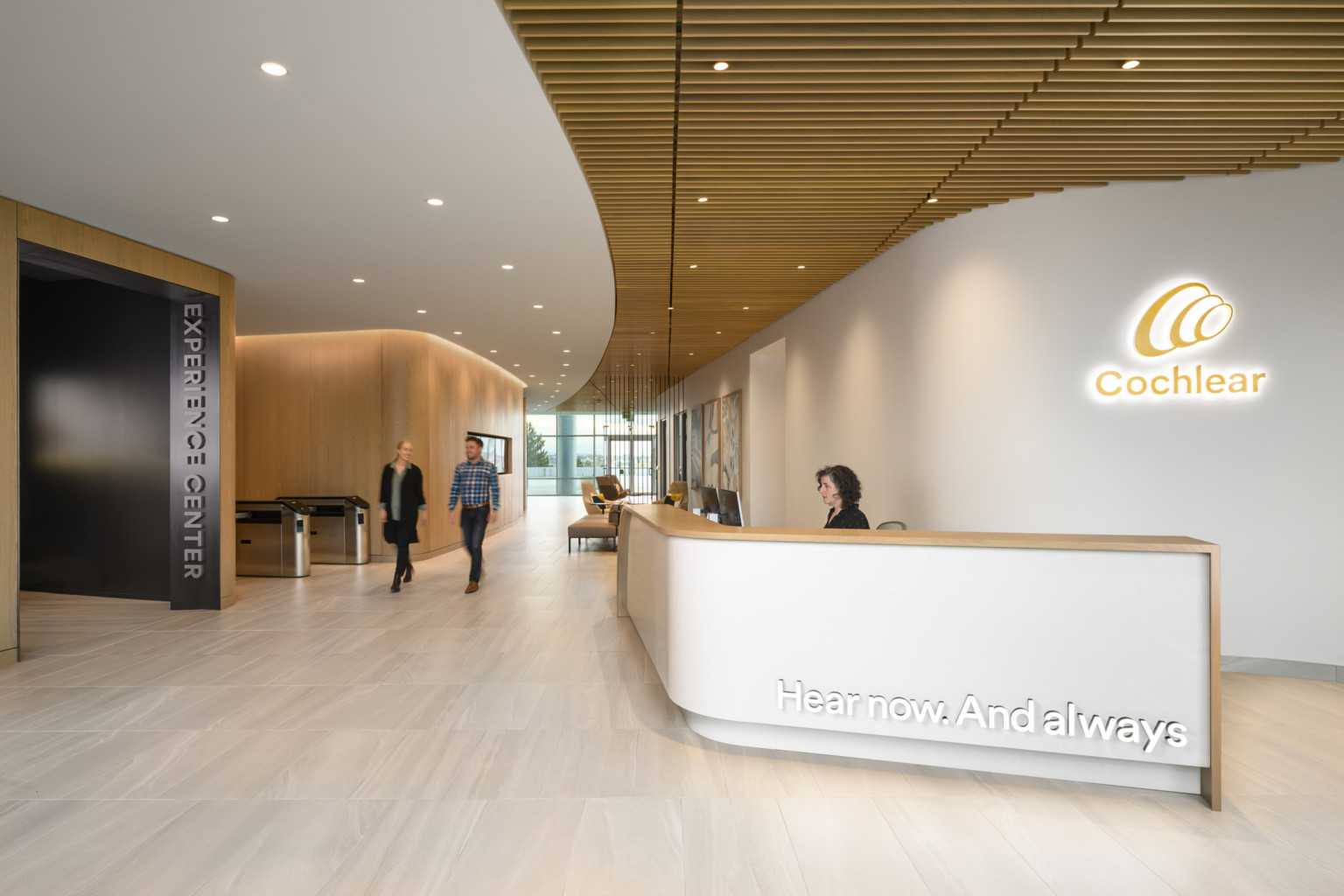 Cochlear North American Headquarters entrance with white reception desk in front of backlit logo with wood ceiling accents