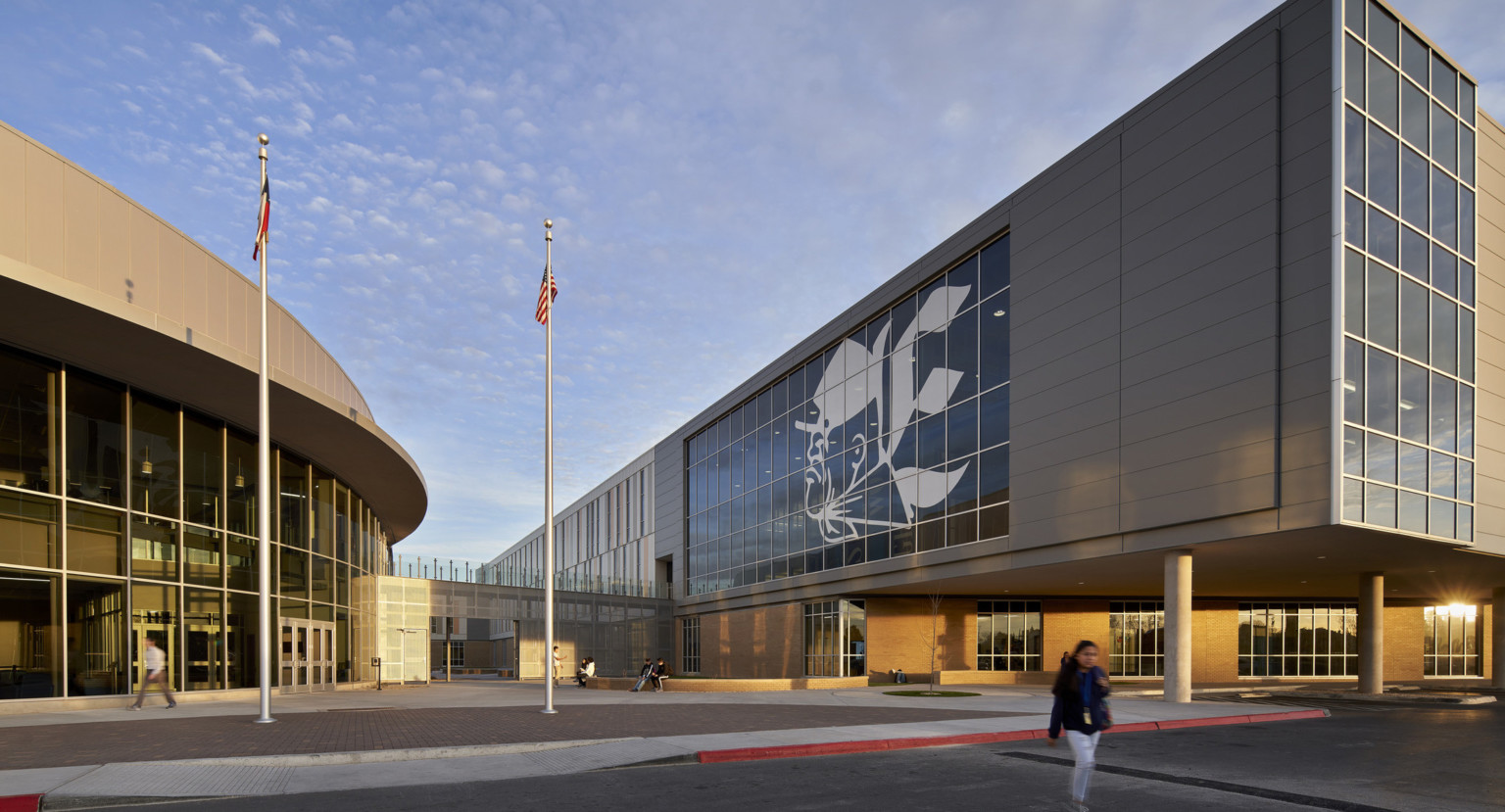 Exterior corner view of same building. Elevated extensions covers walkway below and ends in a wall of windows