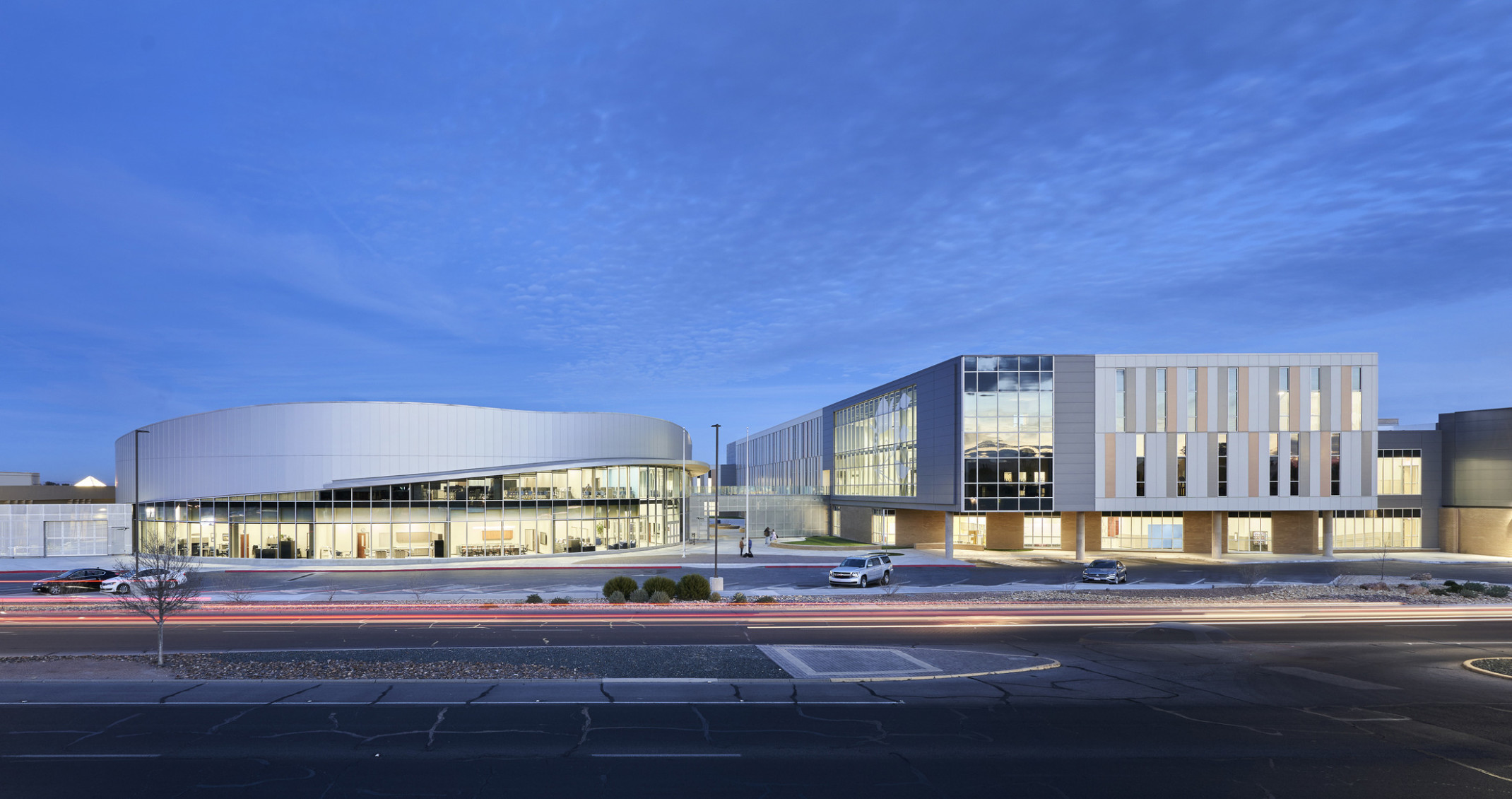 Eastwood High School viewed from the front. 2 glass buildings topped with silver paneling. The left building and panels curve