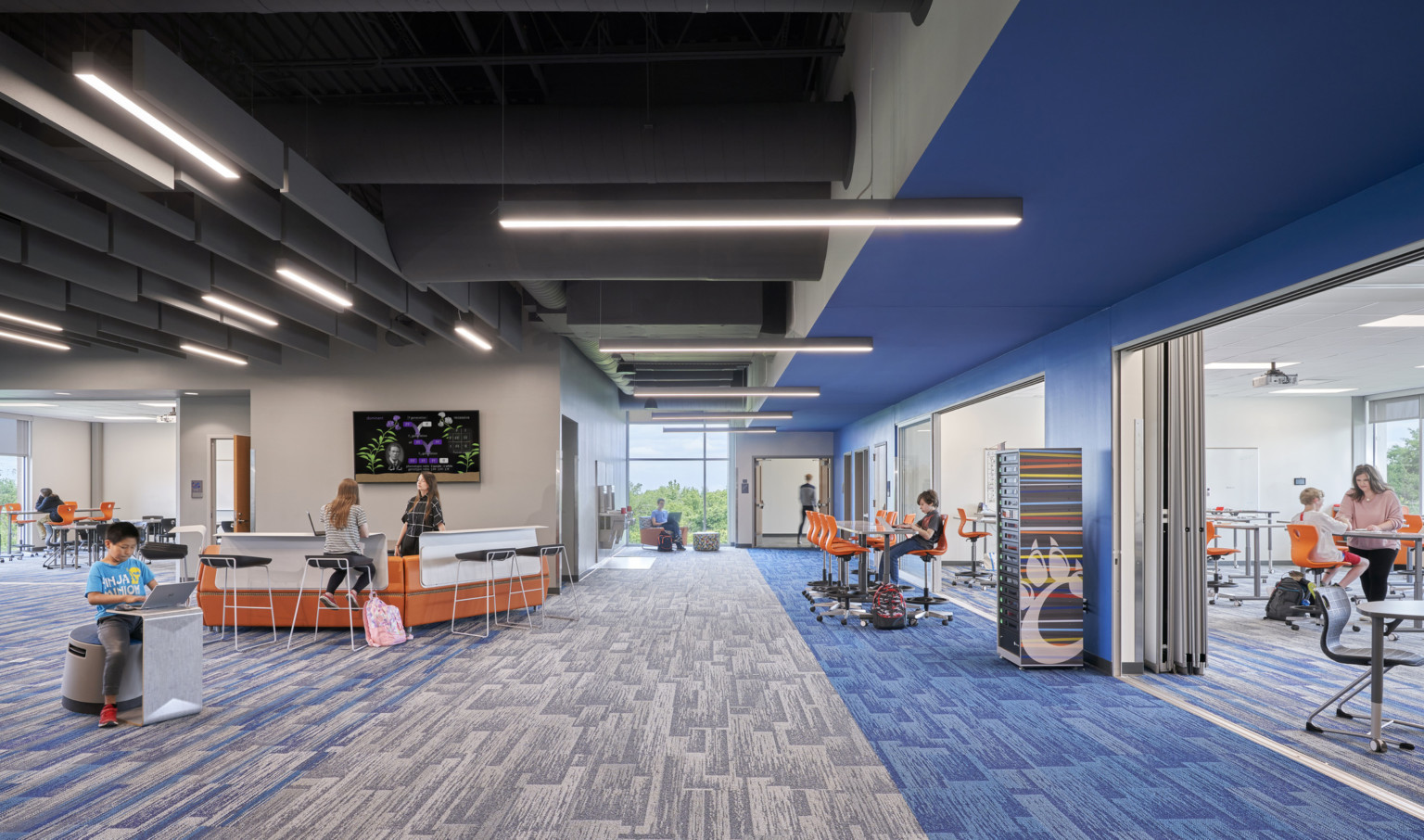 Grey and blue hallway with large flexible walls. Black ceiling with acoustical panels and beam lights