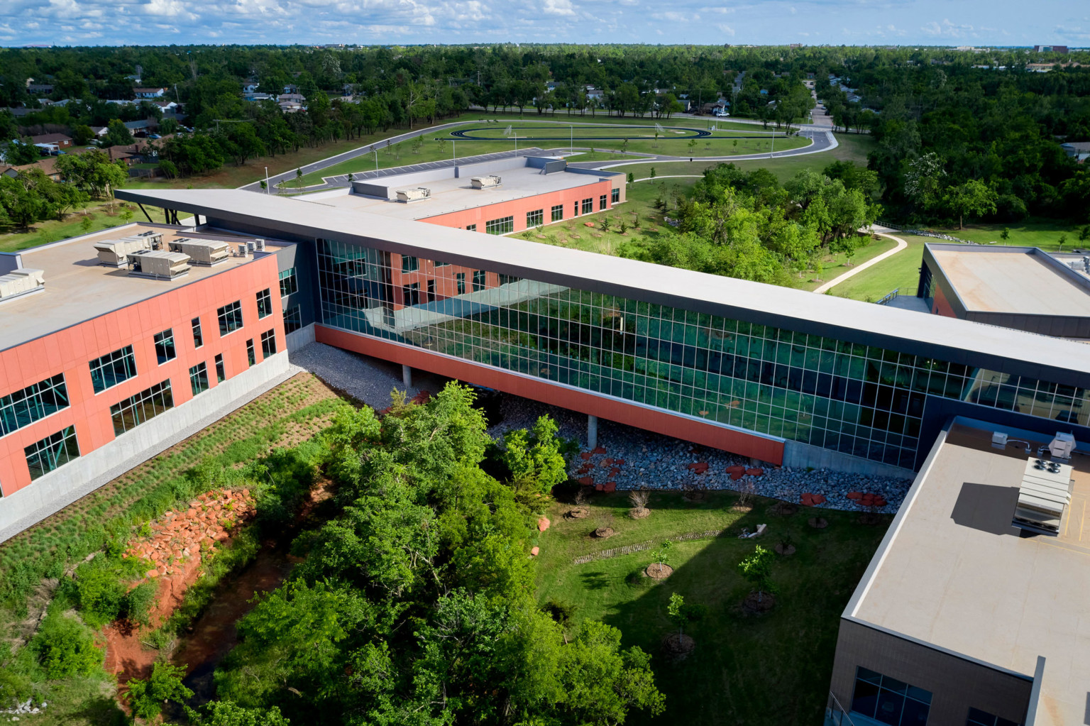 Aerial view of site focused on the long hallway with double height windows connecting two building sections Aerial view of site focused on the long hallway with double height windows connecting two building sections