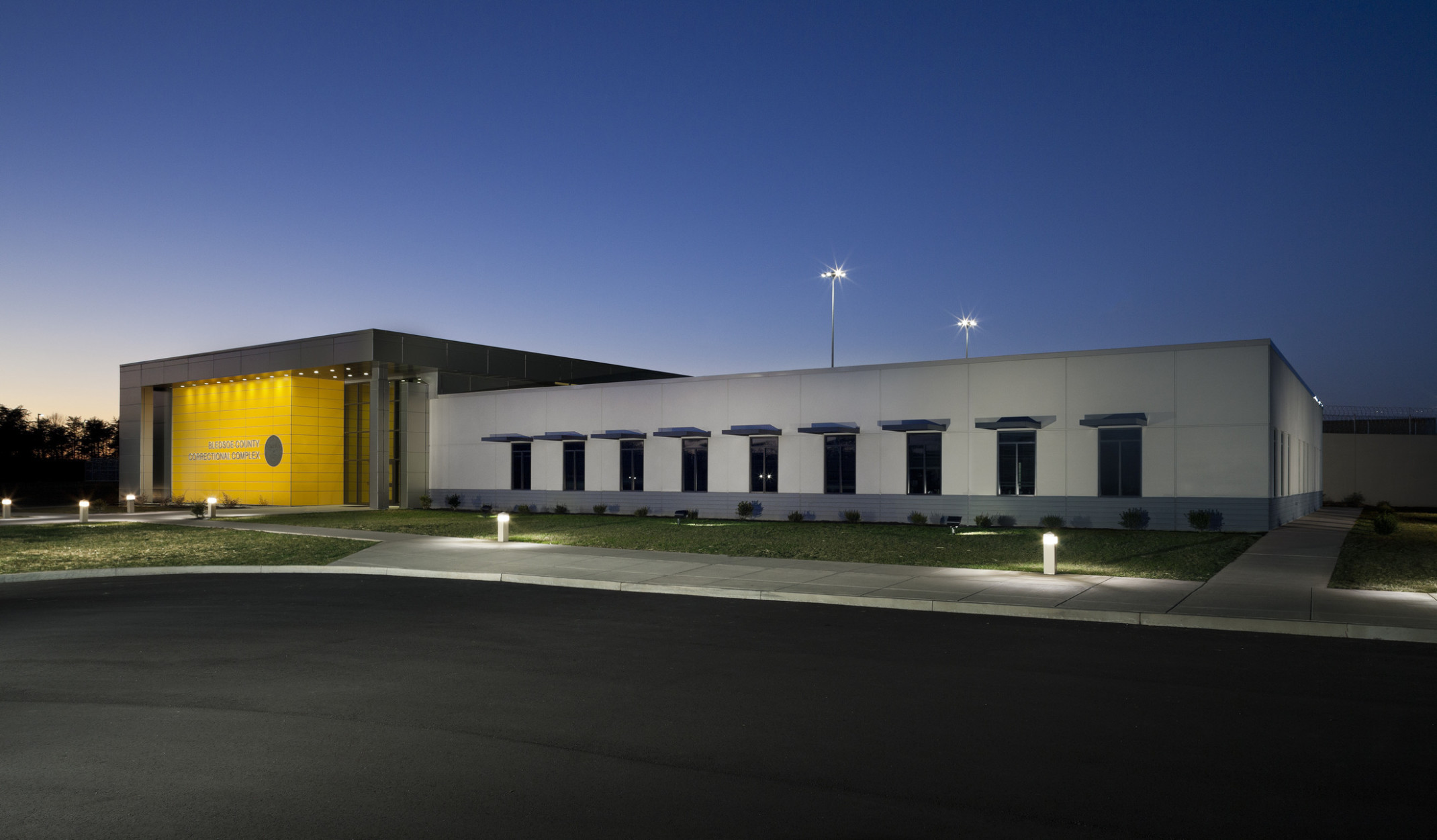 The Bledsoe County Correctional Complex exterior entryway viewed at night. Yellow accent wall is illuminated from above