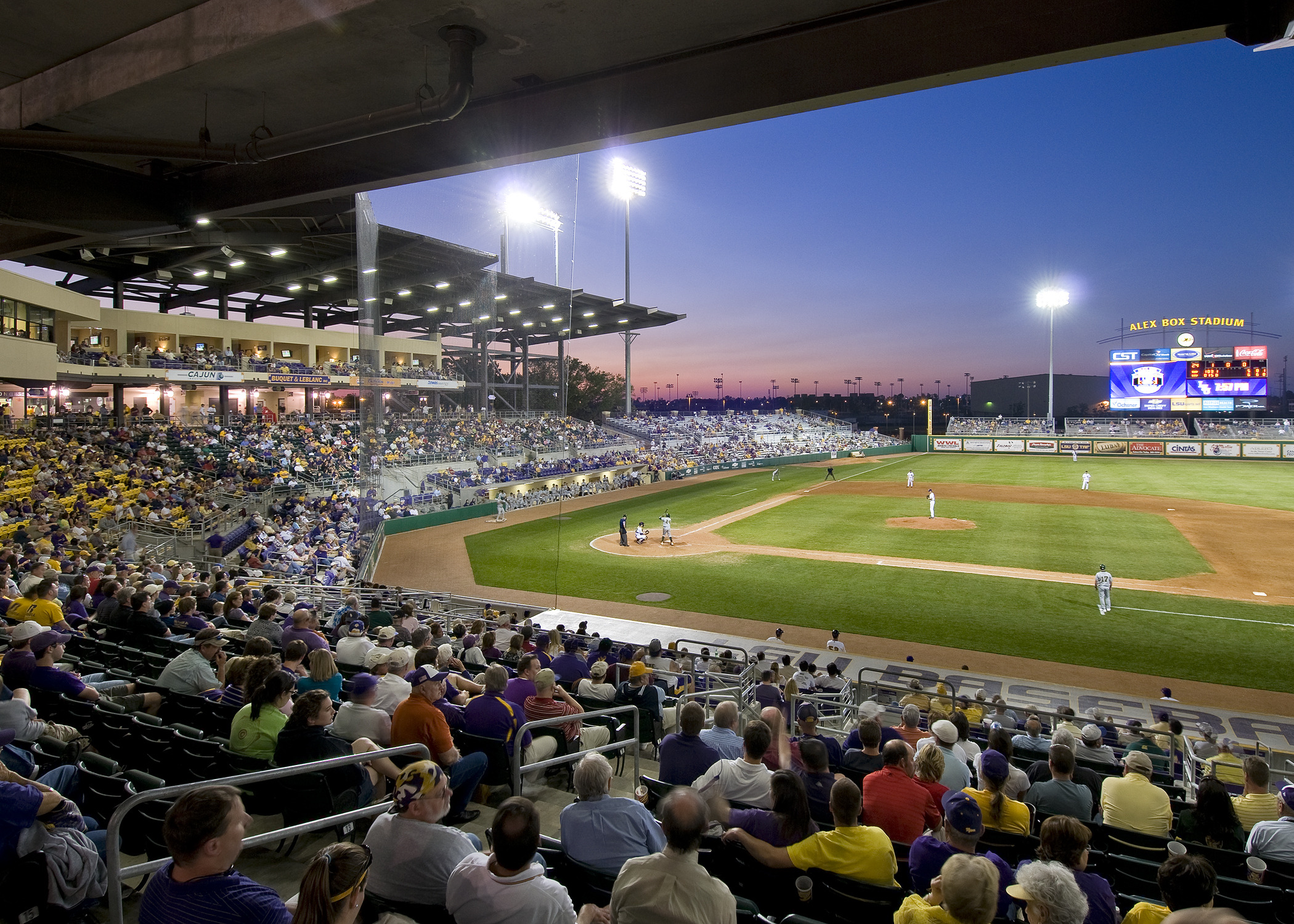 View from first base side across field. Lower deck seating behind left field with jumbotron display and stadium light above