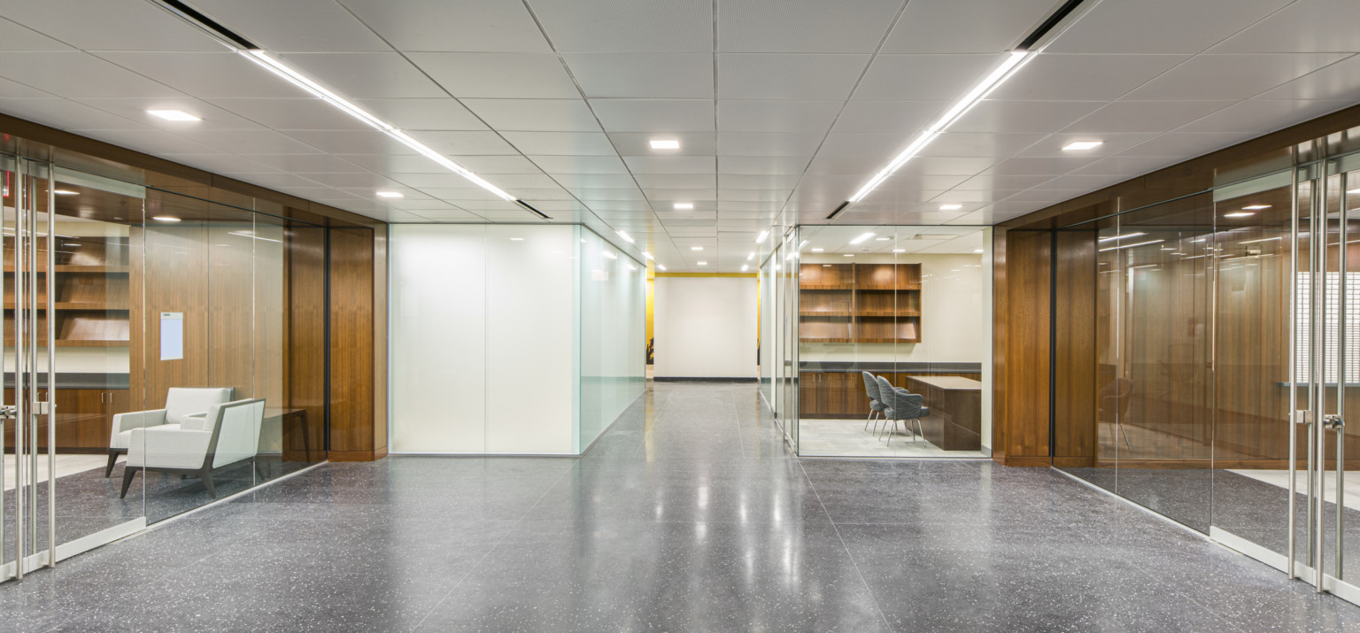 Interior hallway in the GSA Harry S. Truman Federal building with white walls and wood details. Glass offices to either side