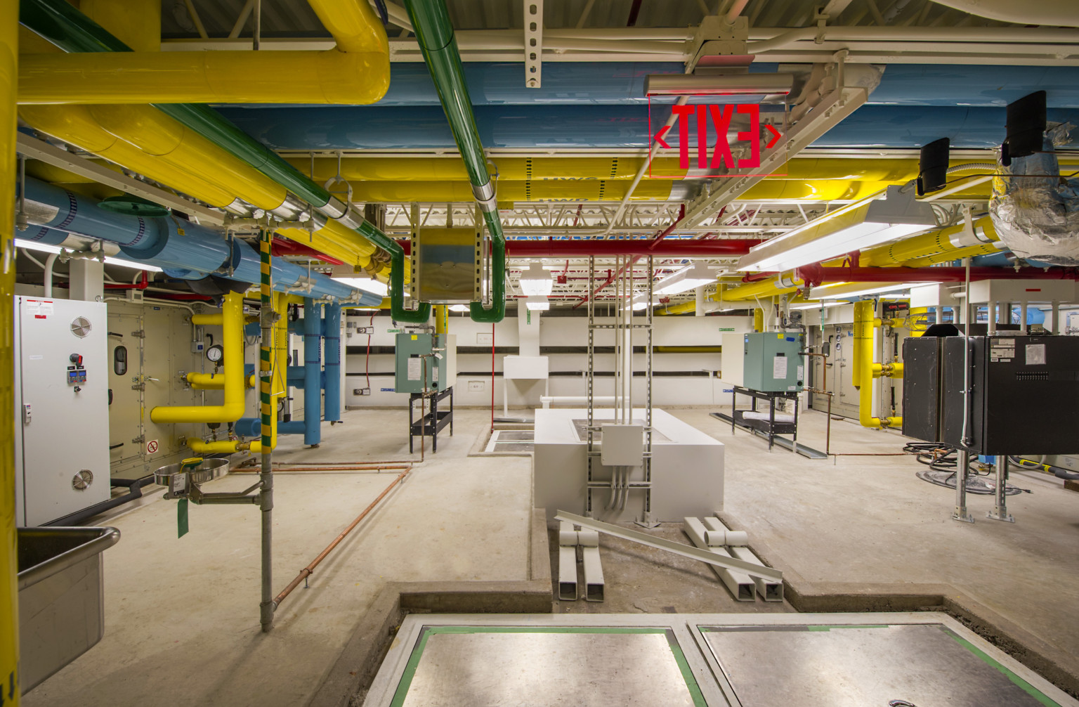 Colorful exposed pipes in white room with mechanical boxes