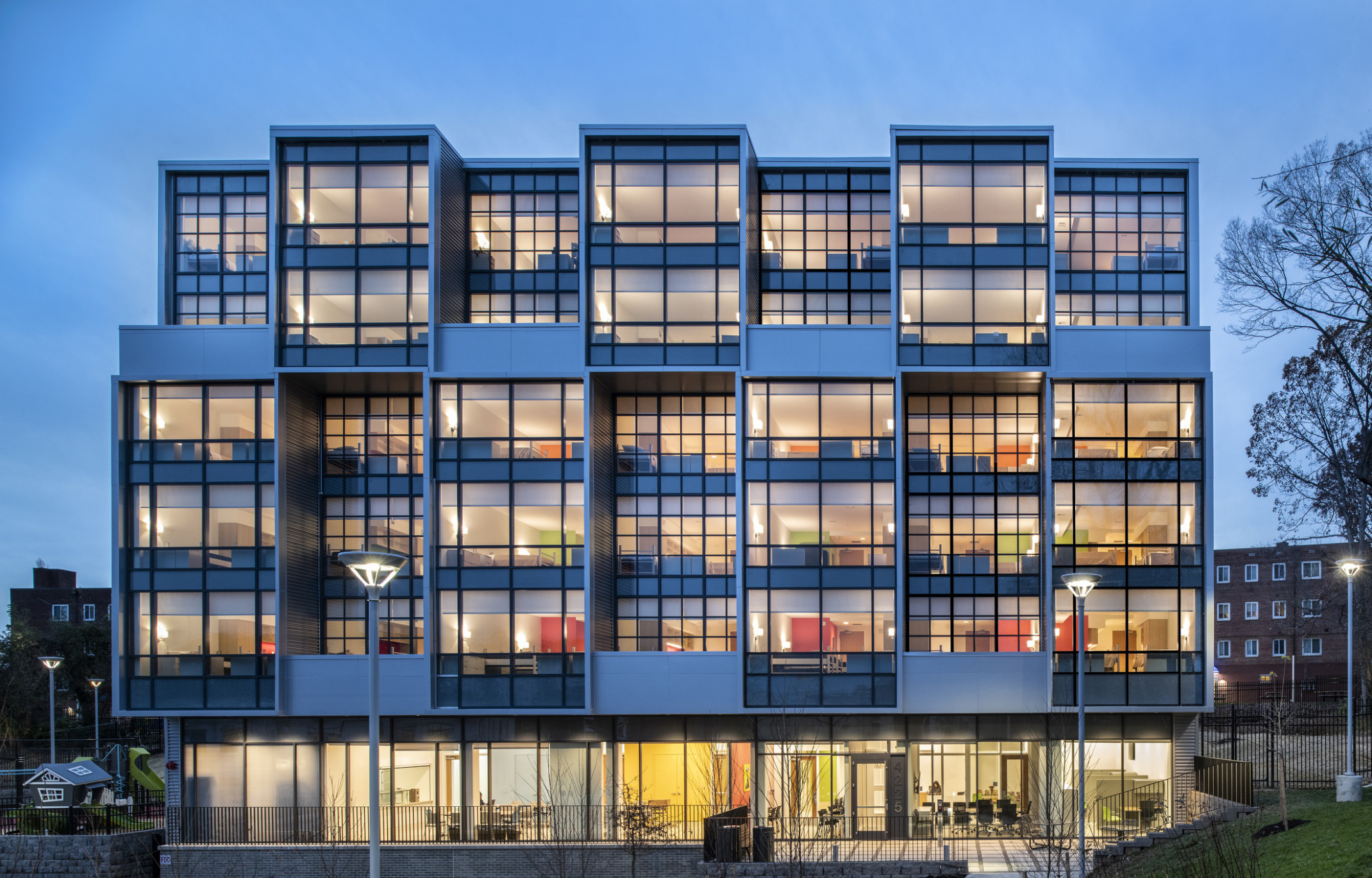 Exterior view of a section the Triumph with window covered facade illuminated at night with interior rooms visible