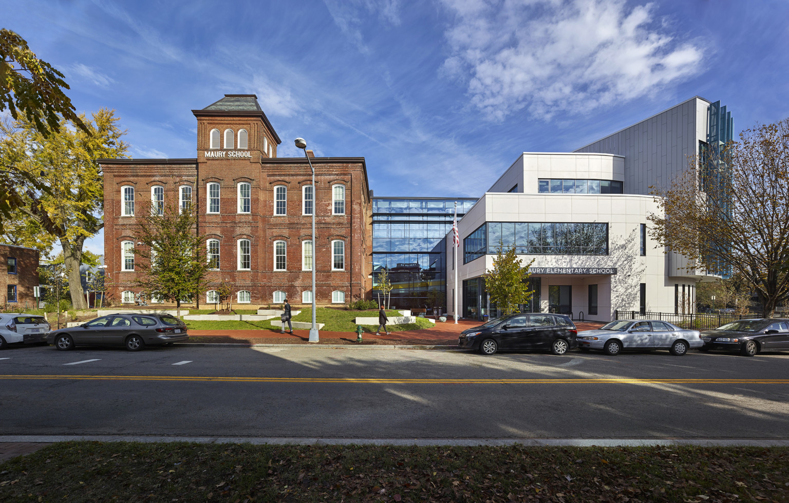 Maury Elementary School, a white panel facade building with windows connects at back by a glass atrium to brick Maury School