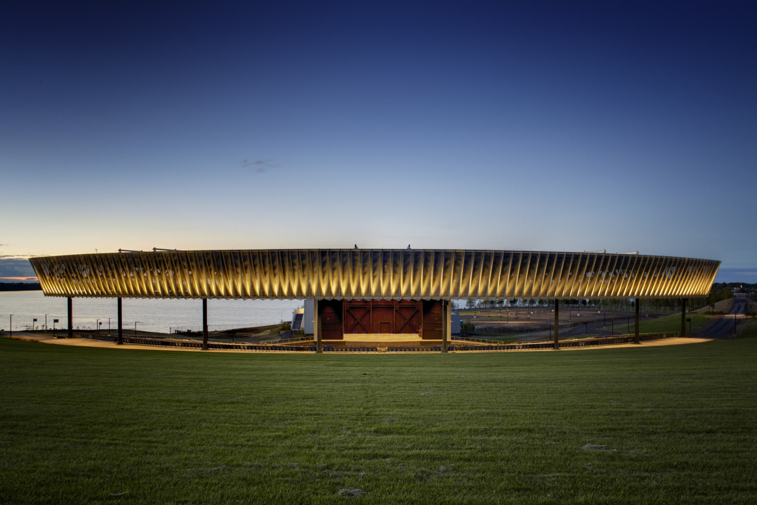 Paneled fascia partially illuminated from bottom over an amphitheater next to a body of water