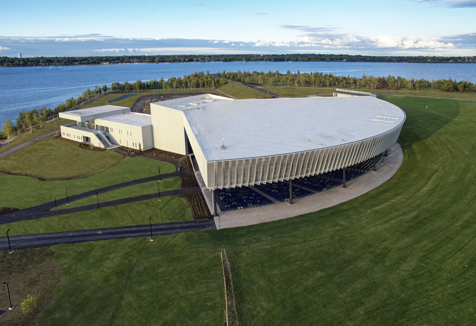 Amphitheater from above in a large green field with white building connected behind