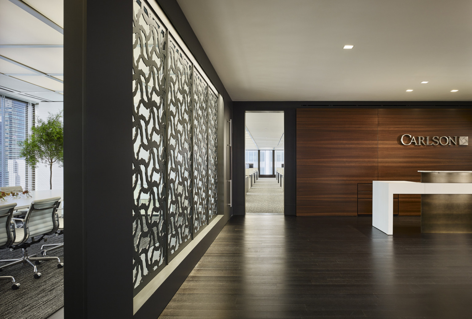 Carlson Capital New York office white reception desk with gold accent in wood room. Partition, left, with organic cutouts