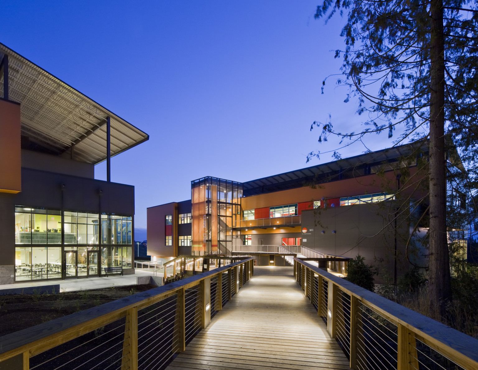 Marysville Getchell High School pedestrian bridge crosses to 2 buildings. Glass entrances and orange accents on each building