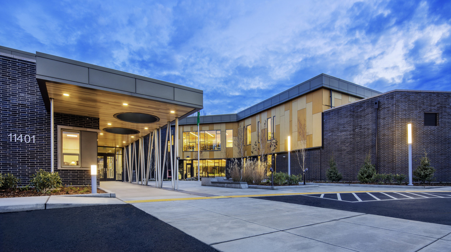 Building entrance viewed from driveway. The building dark brick with wood panel details