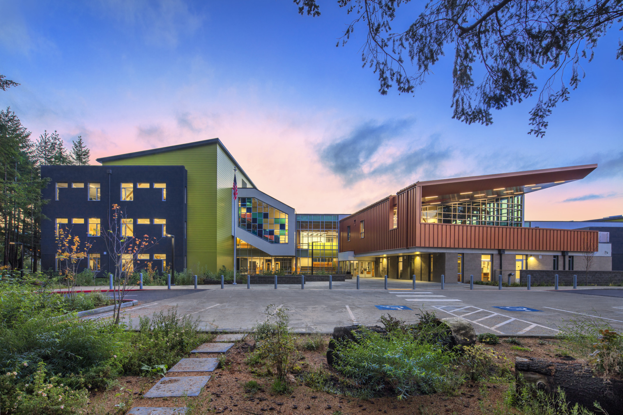 Wainwright Intermediate School is composed of 3 sections. Left is yellow with black wrap facade, right orange, glass middle