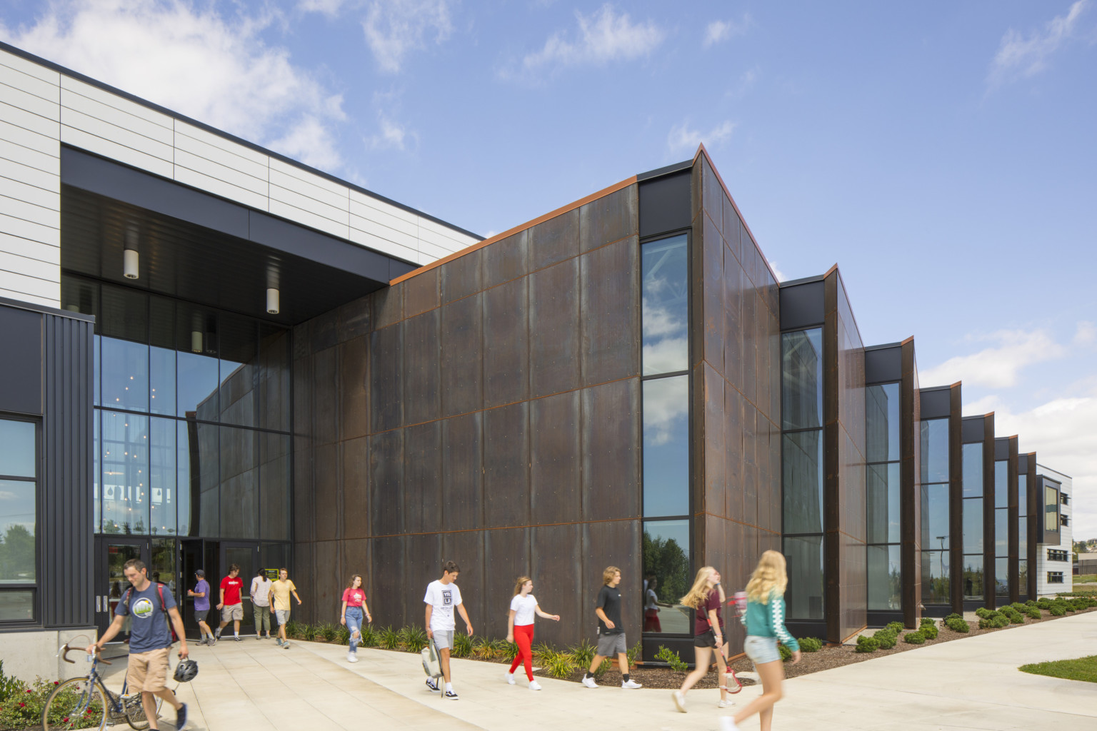 Front entrance of building looking towards brown stepped angled building extensions with strips on windows at end