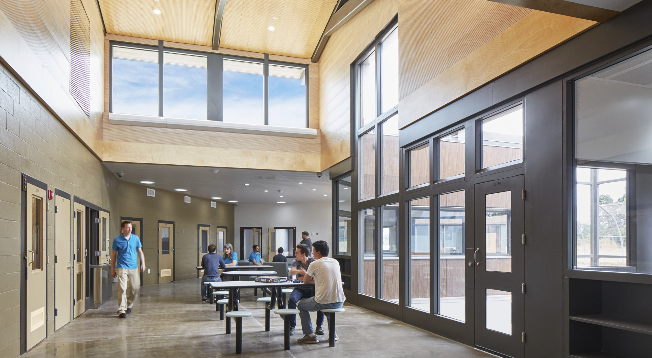 Oregon Youth Authority Maclaren Campus entry hallway. Black framed double height windows at entrance and wood upper walls