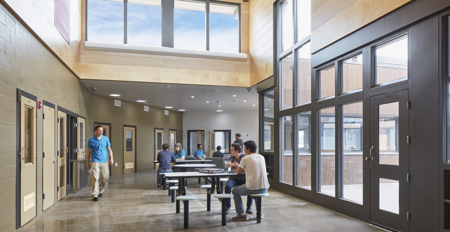 Oregon Youth Authority Maclaren Campus entry hallway. Black framed double height windows at entrance and wood upper walls