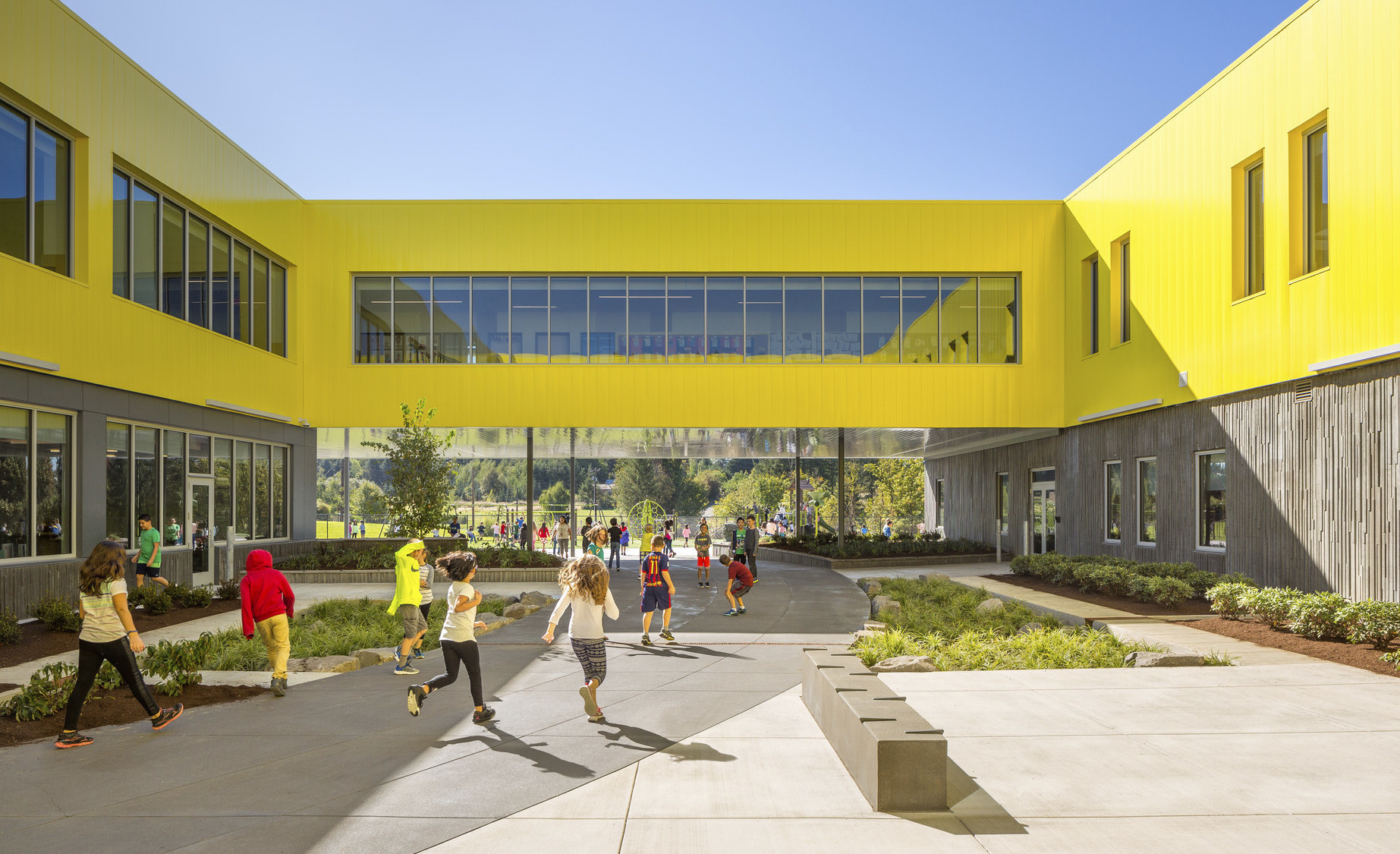 Beaverton School District's Sato Elementary School exterior. Grey textured walls below yellow 2nd floor with skywalk between