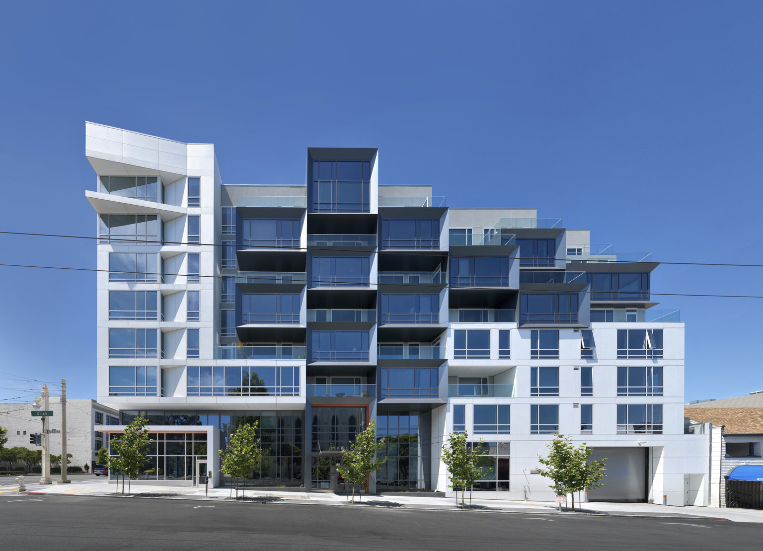 Side of building with white wrapped facade on left, glass facade to right with balconies in stepped arrangement