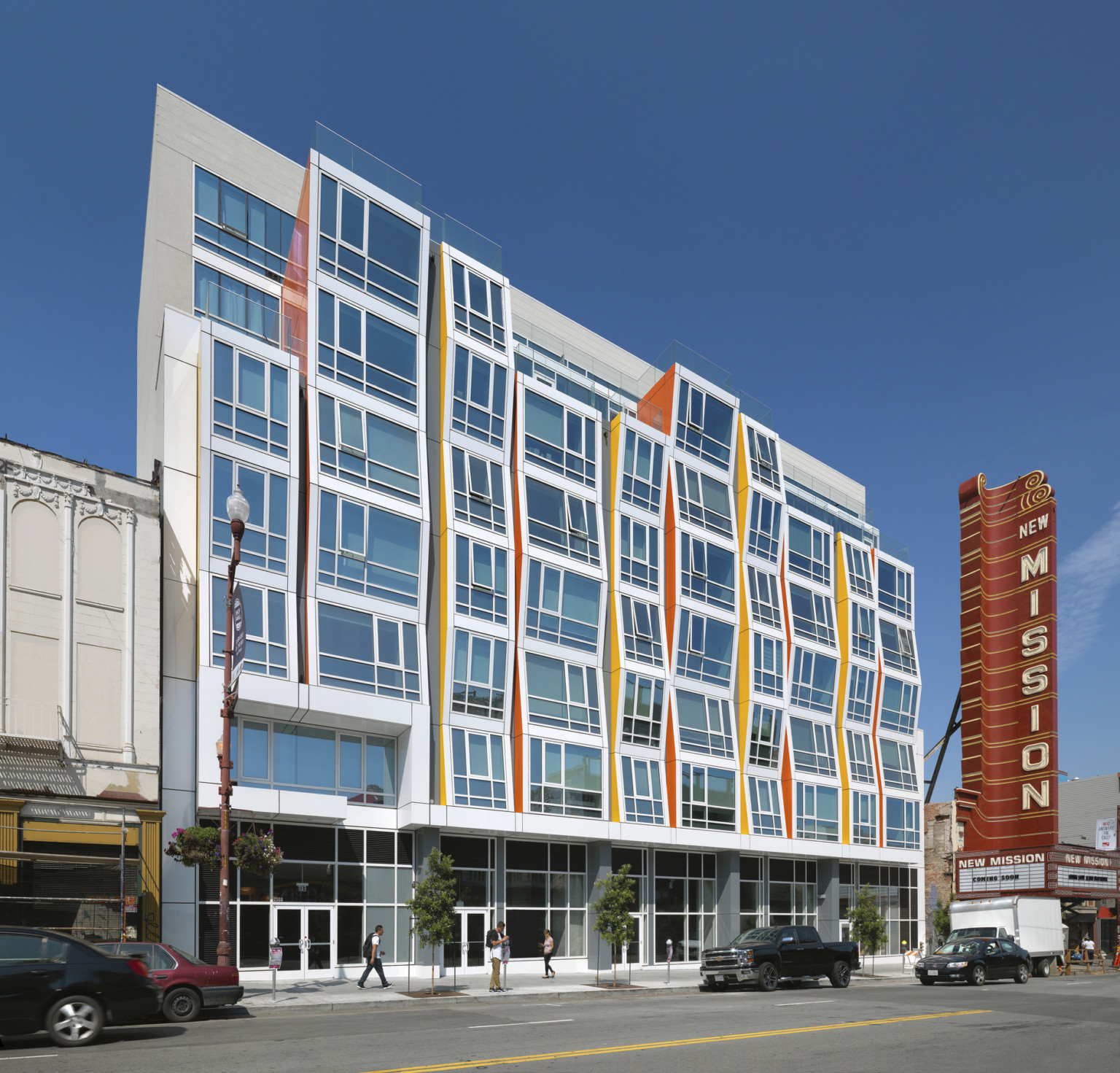 The Vida building with white and glass facade, orange and yellow accents. Vertical stripes down building create angled waves